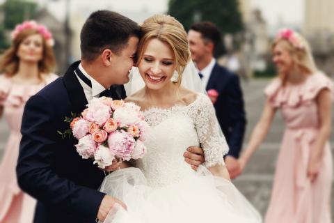 Groom whispering in laughing bride's ear at the ceremony